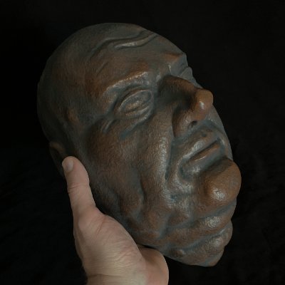 A hand supports the mask to display the detailed left facial profile and jawline.
