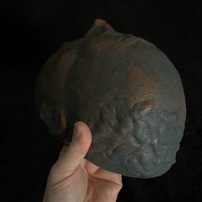 An angled posterior view held by a hand demonstrates the mask's edge boundary.